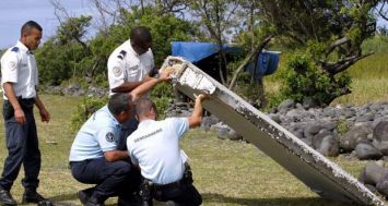 Des gendarmes examinant la pièce d’avion retrouvée sur le rivage de Saint-André par des éboueurs qui ont aussi découvert un bagage sur place. (Crédit photo : Le Quotidien de la Réunion)