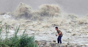 Un habitant ramasse des pierres sur la rive du fleuve Xindian après le passage du typhoon meurtrier Dujuan à Nouveau Taipei, le 29 septembre 2015. [Photo: AFP] 