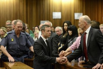 Oscar Pistorius serre la main de son oncle Arnold Pistorius avant d'être emmené en prison à l'issue de son procès le 21 octobre 2014 à Pretoria.