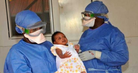 La petite Noubia dans les bras d'une soignante le 28 novembre 2015 à Conakry quelques jours après avoir été déclarée guérie du virus Ebola.