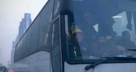 Des salariés chinois prennent un bus devant un chantier à Pékin le 28 décembre 2015.