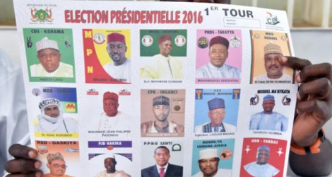 Un employé d'un bureau de vote montre les portraits des différents candidats à l'élection présidentielle au Niger, à Niamey, le 21 février 2016.
