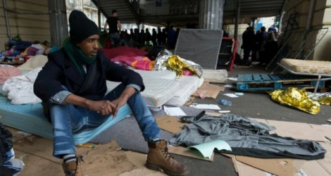 Un migrant assis sur un matelas dans un camp sous la station de métro Stalingrad à Paris le 24 mars 2016 