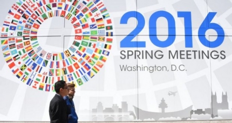 Deux hommes passent devant un panneau annonçant le meeting du monde de la finance à Washington, le 13 avril 2016 