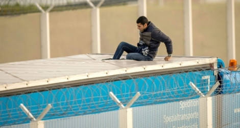 Un migrant est monté sur le toit d'un camion à Calais à l'entrée du tunnel sous la Manche pour pouvoir se rendre clandestinement en Grande-Bretagne, le 17 décembre 2015.