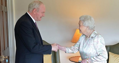 Le vice-Premier ministre d'Irlande du Nord, Martin McGuinness, en tendant sa main à la monarque sous l’œil des caméras.