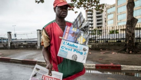 Un vendeur de journaux cherche des clients dans une rue de Libreville le 29 août 2016, tendant ses journaux couvrant le résultat de l'élection présidentielle 