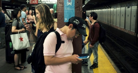 Des personnes regardent leurs smartphones en attendant le train à New York le 1er juillet 2016.