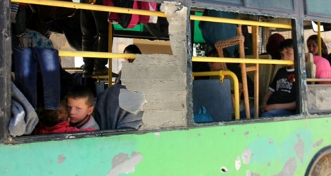 Des Syriens originaires de Foua et Kafraya sont assis à l'intérieur d'un bus à Rachidine le 20 avril 2017 en attendant leur évacuation.