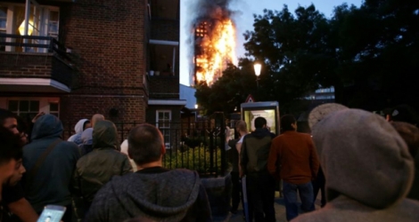 Des résidents regarde le gigantesque incendie qui ravage une tour d'habitation, le 14 juin 2017 à Londres.