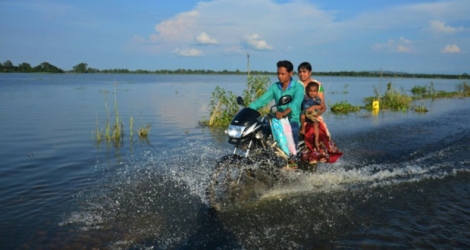 Une famille indienne passe sur une route inondée à Assam, dans le nord-est de l'Inde, le 13 juillet 2017.