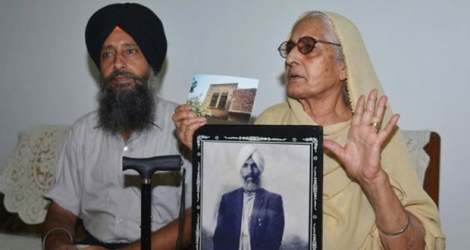 Sushwant Kaur, 78 ans, (d), assise à côté de son fils Jaswinder Singh (g), montre la photo de son défunt père, Sulkhan Singh, le 5 juillet 2017 à Amritsar, en Inde 