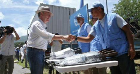 Photo fournie par la présidence colombienne montrant le président Juan Manuel Santos (g) serrant la main d'un membre de l'ONU au moment de fermer les containers des dernières armes rendues par les Farc à Pondores au nord de la Colombie, le 15 août 2017 