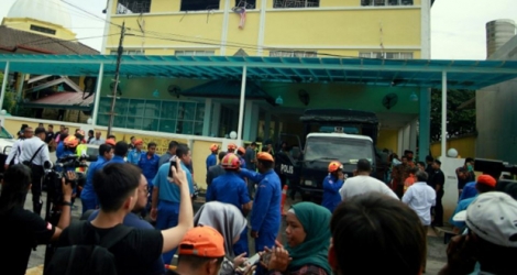 Des pompiers et secouristes devant une école religieuse où s'est déclaré un incendie, le 14 septembre 2017 à Kuala Lumpur, en Malaisie.