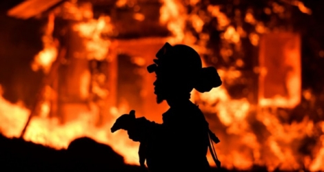 Un pompier se tient devant une maison en flammes dans la région de Napa, en Californie, le 9 octobre
