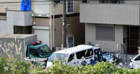 Un homme (haut droite) regarde des policiers se rassembler devant un appartement à Zama , près de Tokyo, où neuf corps ont été retrouvés.