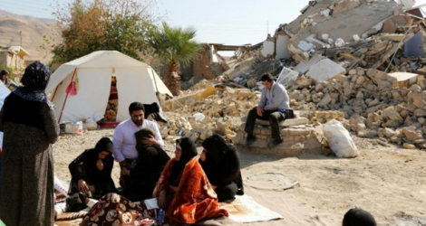 Des Iraniens assis devant leurs maisons en ruine après le séisme ayant frappé l'ouest de l'Iran, le 15 novembre 2017 dans le village de Kouik 