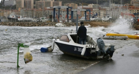 Un homme debout dans son bateau poussé par les vagues à Ajaccio (France), sur la mer méditerranée, le 11 décembre 2017 