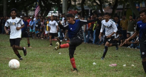 Un Rohingya de l'équipe Cheras Harimau frappe la balle tandis que des joueurs de Selangor (en blanc) le regardent lors d'un tournoi destiné aux réfugiés, à l'occasion des célébrations de la fin du ramadan en Malaisie, à Kuala Lumpur, le 18 juin 2018.