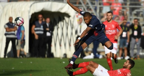 L'attaquant du PSG Kylian Mbappé tente d'éviter un tacle du milieu nîmois Téji Savanier au stade des Costières.