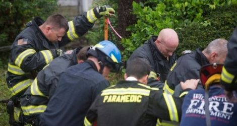 Des pompiers en opération prient sur les lieux où une femme et son enfant ont été tués par la chute d'un arbre lors du passage de l'ouragan Florence, le 14 septembre 2018 à Wilmington, en Caroline du Nord 