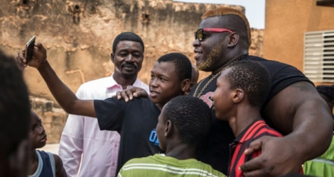 Le Burkinabè Ahmed Al-Hassan Sanou, alias Iron Biby, pose avec de jeunes fans à Bobo-Dioulasso, le 24 septembre 2018.