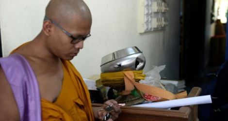 Un moine bouddhiste près d'un bol d'aumônes (centre) troué par les balles des assaillants qui ont tué deux moines et en ont blessé deux autres au temple de Rattanaupap dans le sud de la Thaïlande, le 19 janvier 2019.