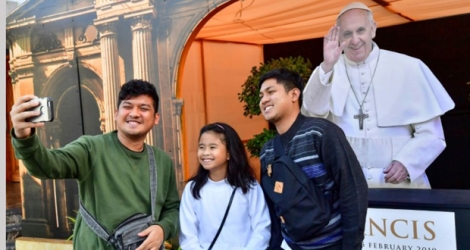 Des fidèles catholiques prennent un selfie à côté d'une photographie du pape François, devant l'église Sainte Marie à Dubaï, aux Emirats arabes unis, le 30 janvier 2019.