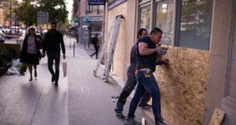 Installation de panneaux de bois pour protéger la vitrine d'un magasin avant le défilé du 1er mai, à Paris le 30 avril 2019.