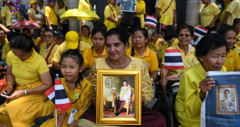 Des Thaïlandaises tiennent le portrait du roi Maha Vajiralongkorn, près du Grand palais, en attendant la grande parade pour son couronnement dans les rues de Bangkok, le 5 mai 2019.