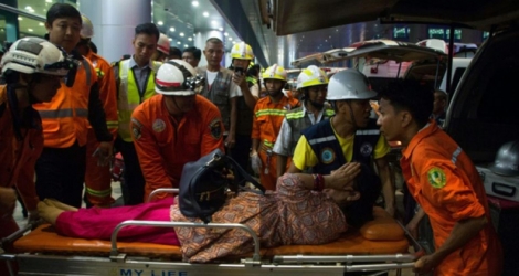 Des secouristes évacuent une blessée après la sortie de piste d'un avion de Bangladesh Airlines à l'aéroport de Rangoun, Birmanie, le 8 mai 2019.