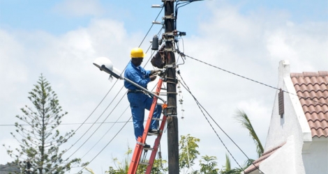 Photo d’illustration: l’employé du Central Electricity Board réparait un transformateur sur une échelle posée sur un poteau électrique.
