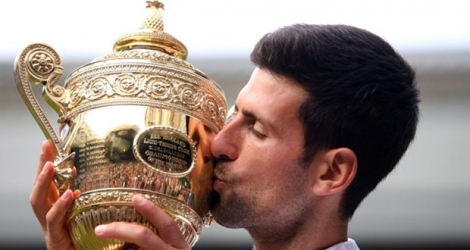 Le Serbe Novak Djokovic embrasse la coupe du Grand Chelem de Wimbledon après une finale de haute volée contre le Suisse Roger Federer, le 14 juillet 2019 à Londres.