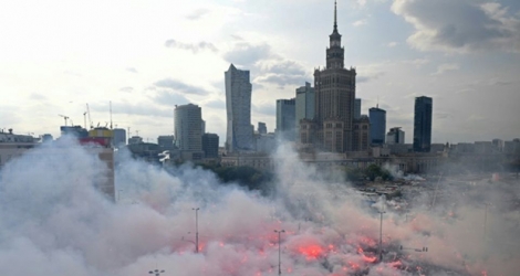 Des Polonais allument des fumigènes et observent une minute de silence pour le 75e anniversaire de l'Insurrection de Varsovie contre l'occupant nazi pendant la Seconde guerre mondiale, le 1er août 2019 à Varsovie.
