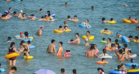 Des baigneurs pataugent dans les vagues à Qingdao, l'une des stations balnéaires les plus réputées de la côte chinoise, le 21 juillet 2019.