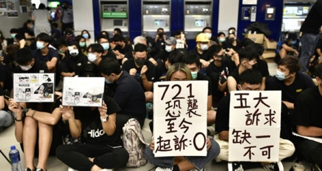 Des manifestants brandissent des pancartes pendant un sit-in à la station de métro Yuen Long à Hong Kong le 21 août 2019.