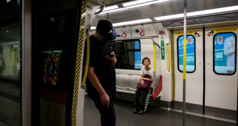 Un manifestant vêtu de noir, couleur emblématique du mouvement, bloque les portes d'une rame de métro pour l'empêcher de partir, le 2 septembre 2019 à Hong Kong. 