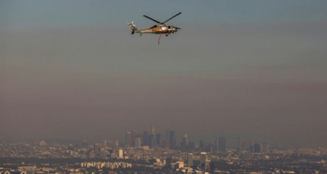 Un hélicoptère des pompiers survole la zone de Los Angeles le 28 octobre 2019 où un violent feu de broussailles s'est déclaré dans la nuit de dimanche à lundi, contraignant plusieurs milliers de personnes à évacuer de manière préventive.