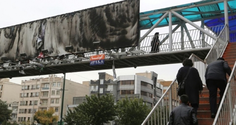 Image prise à Téhéran le 19 novembre 2019, montrant un grand panneau publicitaire au-dessus d'une autoroute urbaine incendié.