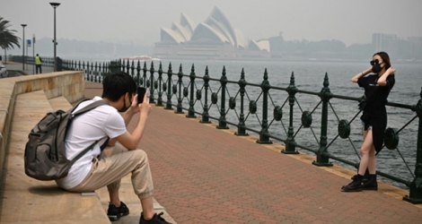 Des touristes portent des masques en raison des fumées toxiques liées aux incendies de forêts, le 10 décembre 2019 à Sydney, en Australie.