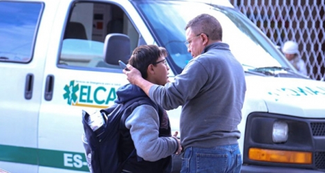 Un homme et son fils devant un véhicule de secours près de l'école de Torreon où un élève de six ans a tué une personne et en a blessé six autres, le 10 janvier 2020.