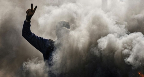 Un manifestant anti-gouvernement fait le V de la victoire au milieu de la fumée émanant de pneus brûlés le 26 janvier 2020 à Najaf, au sud de Bagdad.