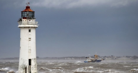 Un bateau de pêche passe le 9 février 2020 devant le phare de New Brighton, dans le nord-ouest de l'Angleterre, où la tempête Ciara est arrivée Photo Paul ELLIS . AFP