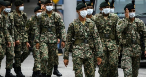 Des soldats protégés par des masques sont déployés dans les rues de Kuala Lumpur, le 22 mars 2020, pour contrôler les mouvements des habitants Photo Mohd RASFAN. AFP