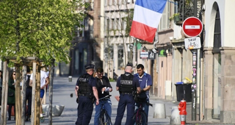 Des policiers contrôlent des passants, vérifiant leur attestation de sortie, le 9 avril 2020 à Strasbourg.