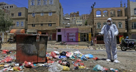 Un volontaire yéménite désinfecte au dessus des poubelles dans un quartier pauvre de Sanaa, la capitale du Yémen en guerre, le 30 mars 2020.