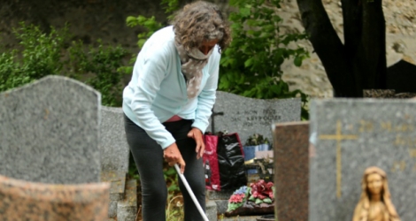 Une femme nettoie une tombe le 28 avril 2020 dans un cimetière de Reims qui vient de rouvrir.