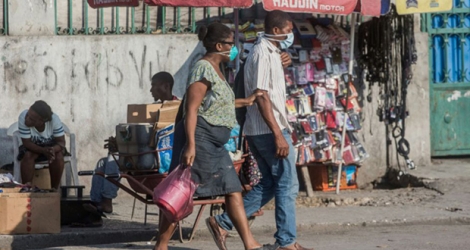 Des personnes portent un masque de protection contre le coronavirus dans une rue de Port-au-Prince, le 26 mars 2020 à Haïti.