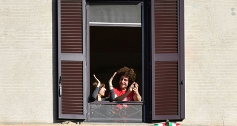 Des Italiens applaudissent depuis leur fenêtre l'assouplissement du confinement, à Rome le 3 mai 2020.