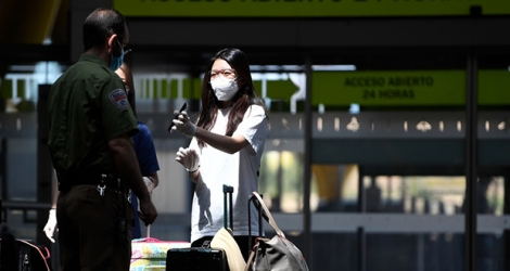 Une passagère montre ses documents de voyage à un agent en poste à l'aéroport Barajas de Madrid, samedi.